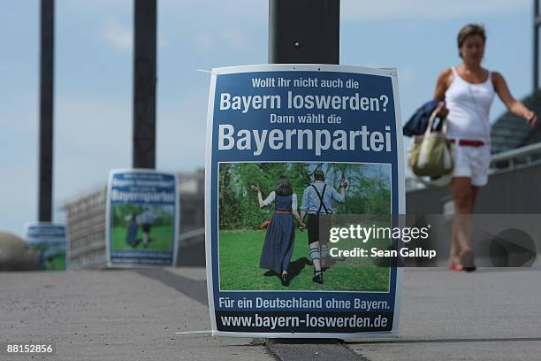 Woman walks past a European elections campaign poster by the Bayernpartei, or Bavaria Party, that reads: "Don't you want to get rid of the Bavarians...