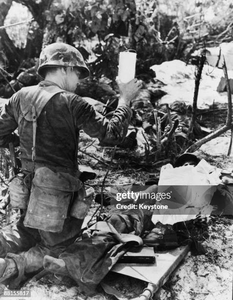 Wounded American Marine receives blood plasma from a navy corpsman during the Battle of Saipan in the Northern Mariana Islands, 27th June 1944.