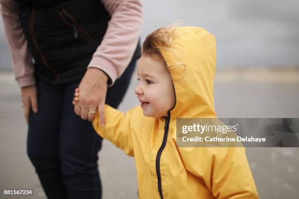 a 2 years old little girl wearing a oilkin on the beach - girl oilskin stock pictures, royalty-free photos & images