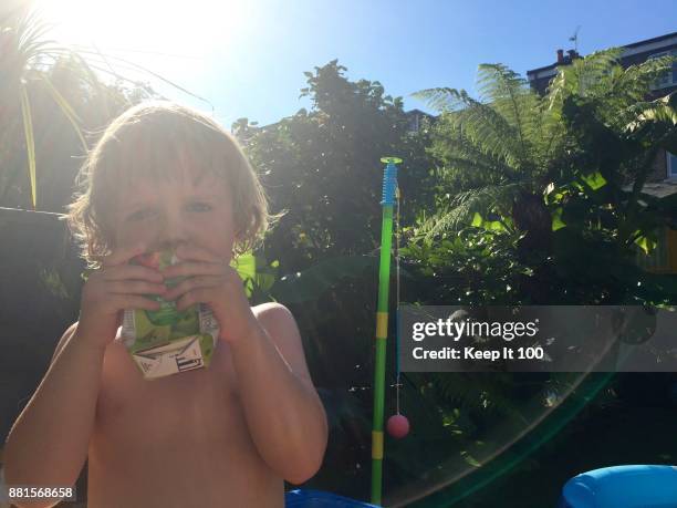 backlit portrait of young child drinking a juice in the sunshine - juice box stock pictures, royalty-free photos & images