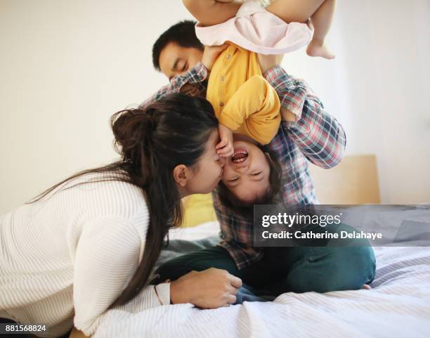 a little girl having fun with her parents on a bed - happy famille france photos et images de collection