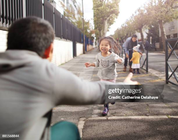a little girl running to the arms of her dad in the street - street running stock pictures, royalty-free photos & images