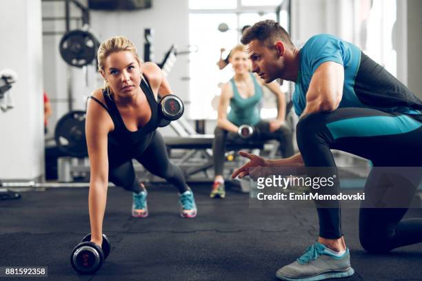 sporty woman doing push-ups under supervision of personal trainer. - personal training stock pictures, royalty-free photos & images