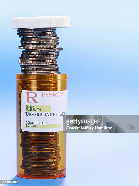 stack of coins in prescription pill bottle - prescription drug costs stock pictures, royalty-free photos & images