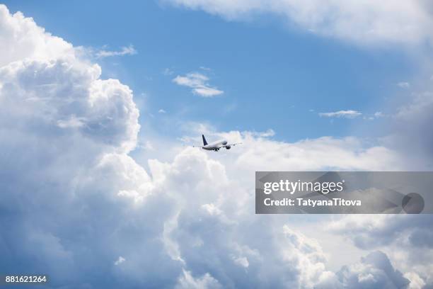 the plane flies in the sky in beautiful clouds - plane in sky stock-fotos und bilder