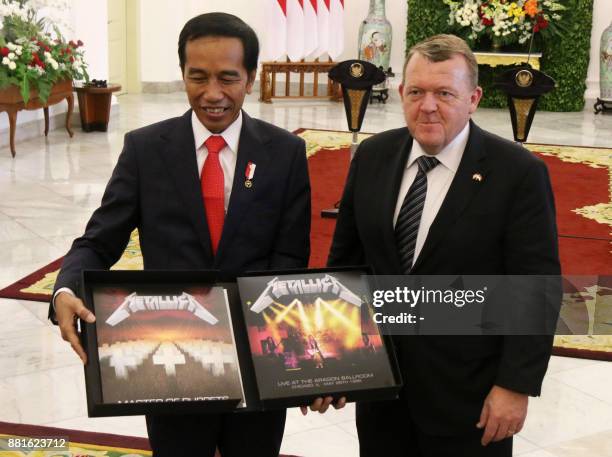 This picture taken on November 28, 2017 shows Indonesian President Joko Widodo displaying a box set of Metallica's Master of Puppets, a gift from...