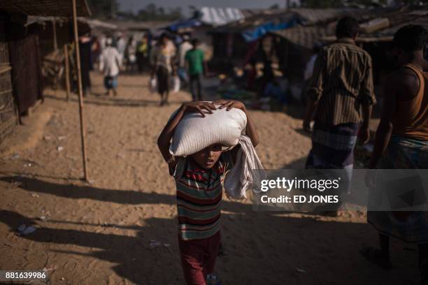 Young Rohingya Muslim refugee carries a sack of rice through the Balukhali refugee camp at Cox's Bazar on November 29, 2017. Rohingya are still...