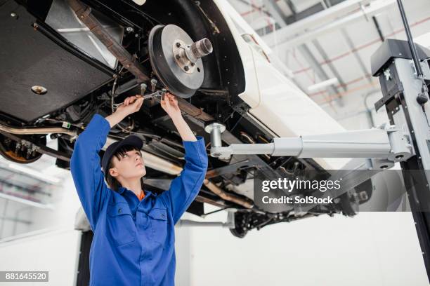 vrouwelijke monteur bezig met een auto - werk in uitvoering stockfoto's en -beelden
