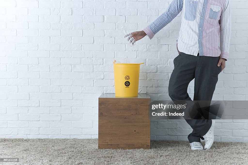 Young man placing water bottle to trash can