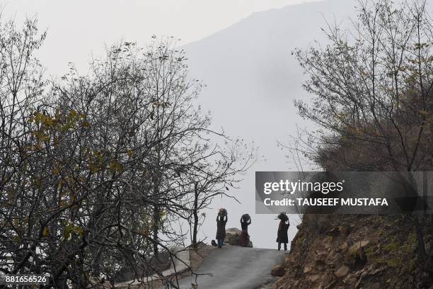 Kashmiri women carry firewood as they walk towards their home in the outskirts of Srinagar on November 29, 2017. A cold wave reached the state of...