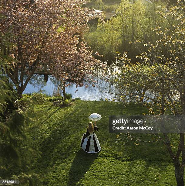 woman in gown carrying parasol - victorian gown fotografías e imágenes de stock