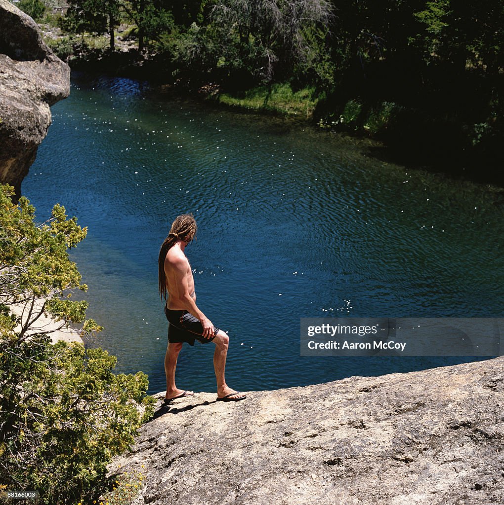 Man standing on rock overlooking river