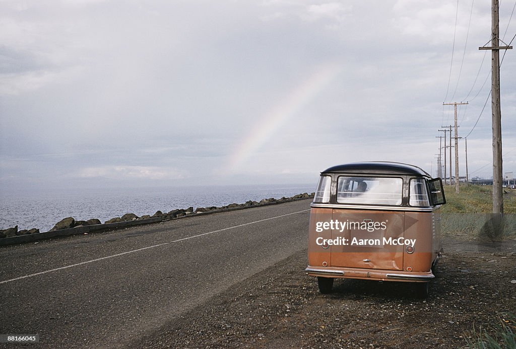 Retro van on side of road with rainbow in horizon