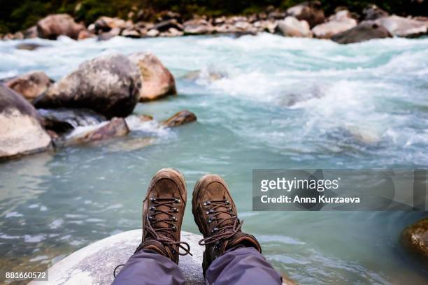 closeup shot of hiker's legs with brown colored hiking boots with a mountain river on the background in himalayas, nepal - pair stock photos et images de collection