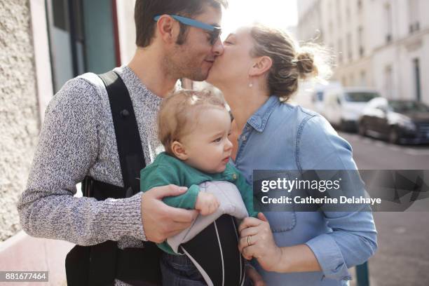 a 8 months old baby boy with his parents in the street - babytrage stock-fotos und bilder