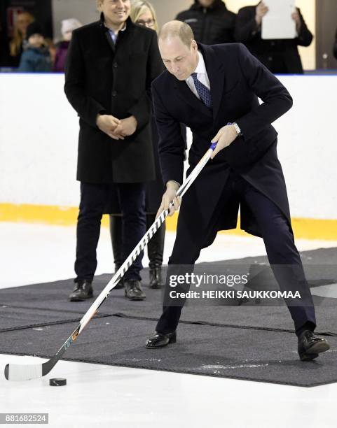 Britain's Prince William, Duke of Cambridge, prepares to shoot the puck during a meeting with members of the Icehearts ice hockey club on November...