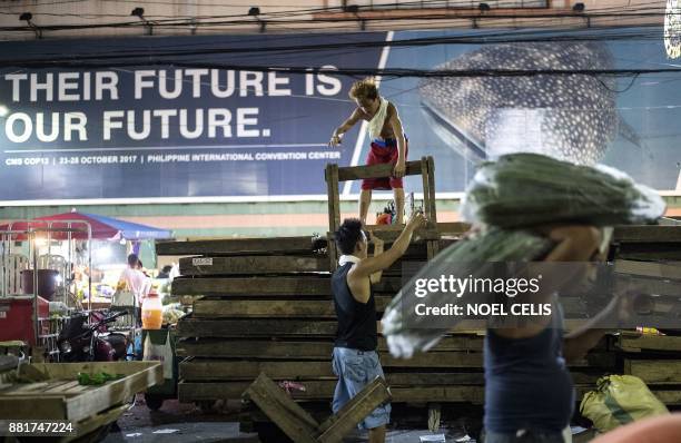 Philippine workers arrange wooden palettes at Divisoria Market in Manila on November 29, 2017. / AFP PHOTO / NOEL CELIS