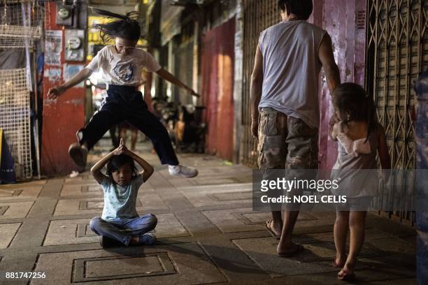 Philippine Children play 'Luksong Tinik' or 'Jump over the thorn' game at Divisoria Market in Manila on November 29, 2017. / AFP PHOTO / NOEL CELIS