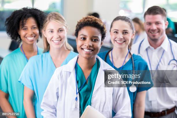 female medical student poses with colleagues in lecture hall - female doctors group stock pictures, royalty-free photos & images