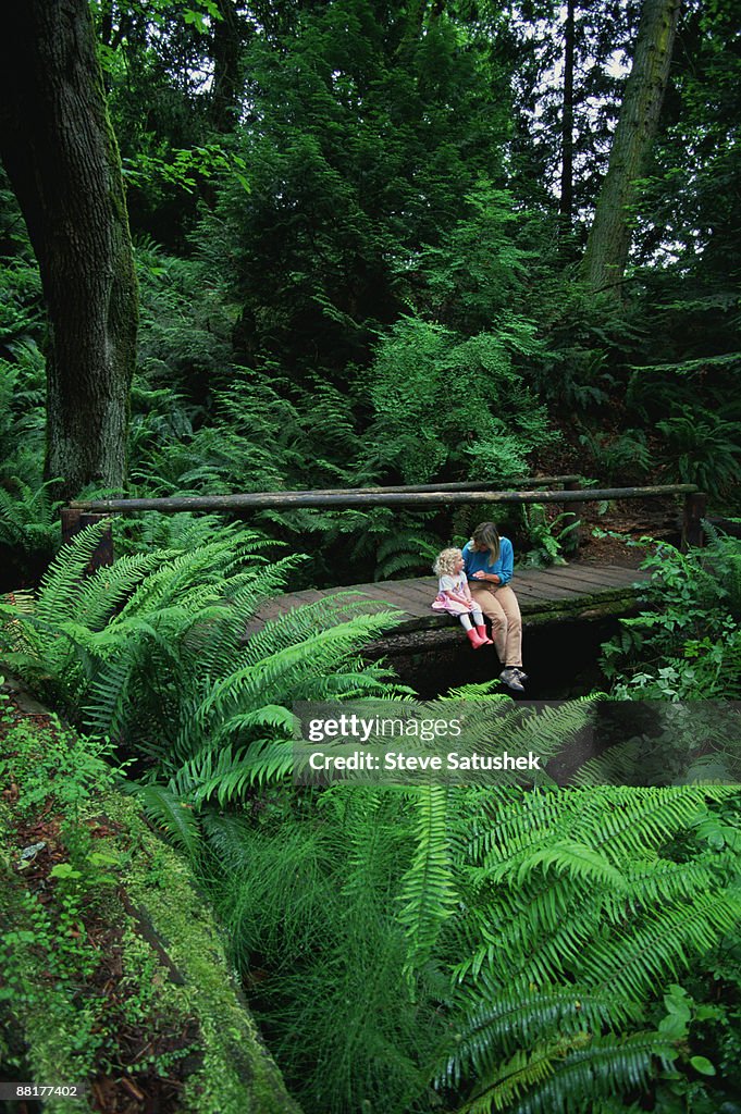 "Mother and daughter sitting in lush woodland , Larrabee State Park , Washington"