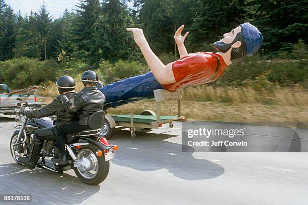 couple riding motorcycle next to paul bunyan statue - funny import stock-fotos und bilder