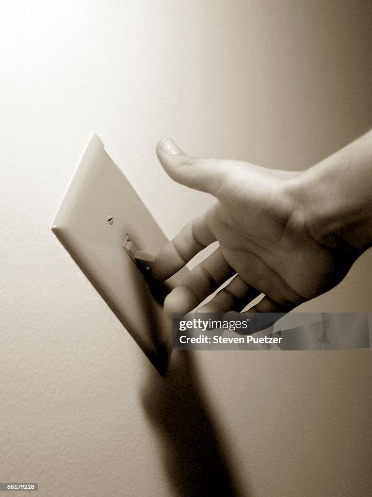 Man's hand about to flip on light switch