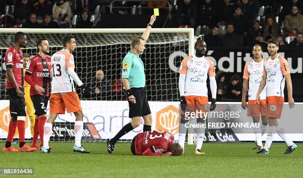 French referee Olivier Thual gives a yellow card to Montpellier's French forward Giovanni Sio during the French L1 footbal match between Guingamp and...