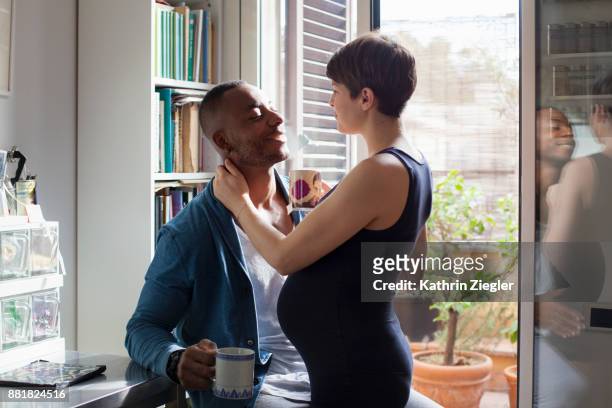 pregnant couple having tea together in kitchen - pregnant couple stock-fotos und bilder