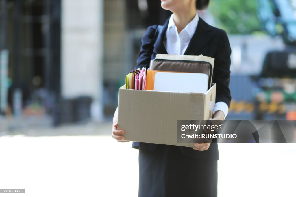 Midsection of businesswoman moving out with cardboard box