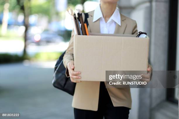 close-up of unemployed businesswoman carrying cardboard box - downsizing 2017 film stock-fotos und bilder