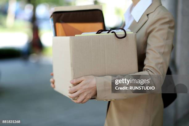 close up of fired businesswoman carrying personal belongings - downsizing 2017 film stock-fotos und bilder