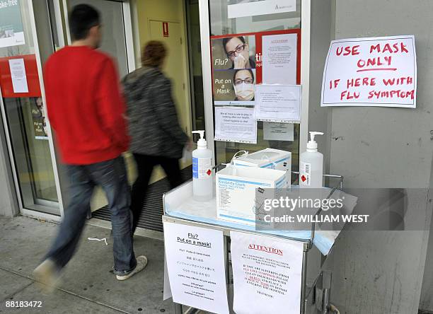 People walk past warning signs as they enter Melbourne's Austin Hospital as Australia raised the swine flu alert level in the worst hit state of...