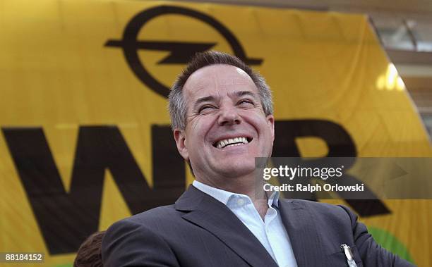 Magna Co-Chief Executive Siegfried Wolf laughs in front of a huge logo of German car maker Adam Opel GmbH, a subsidiary company of U.S. Carmaker...