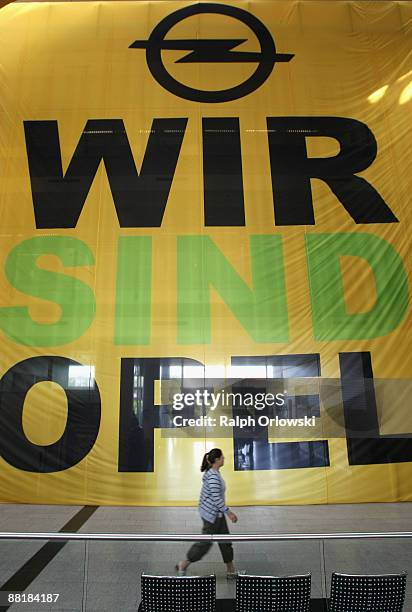 Employee of German car maker Adam Opel GmbH, a subsidiary company of U.S. Carmaker General Motors, walks in front of a huge poster at the...