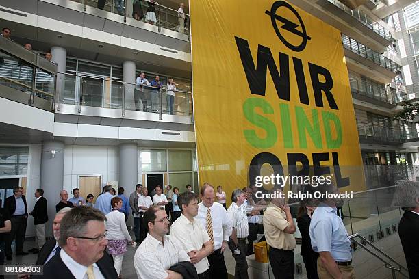 Employees of German car maker Adam Opel GmbH, a subsidiary company of U.S. Carmaker General Motors, stand in front of a a huge poster at the...