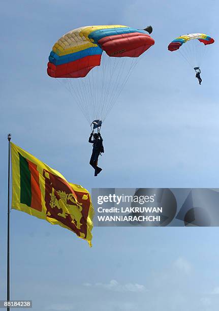 Sri Lankan paragliders land as the national flag flutters during the National Military Victory Celebrations in Colombo on June 3, 2009. Sri Lanka's...