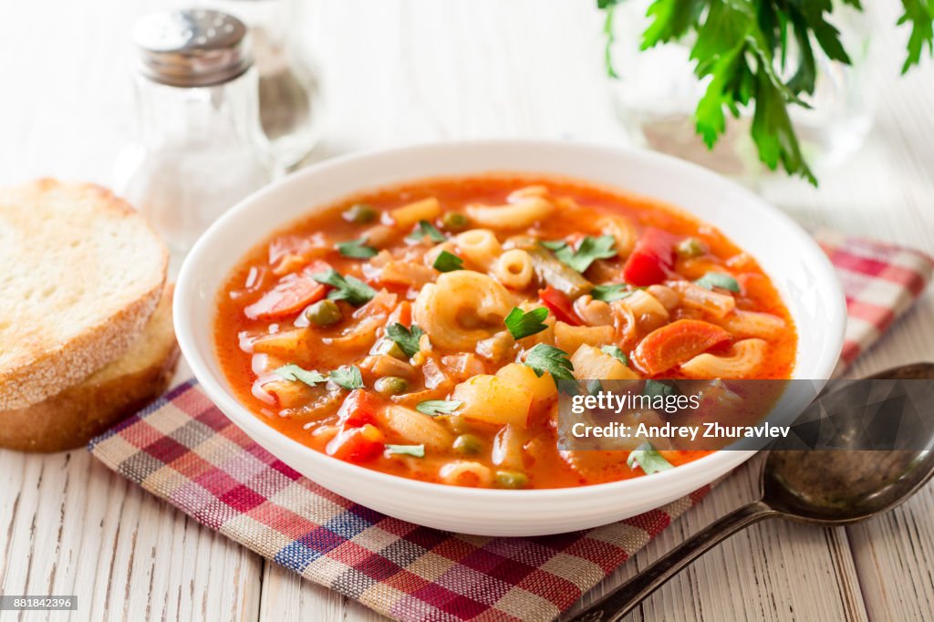 Sopa de minestrone italiano sobre fondo blanco de madera.