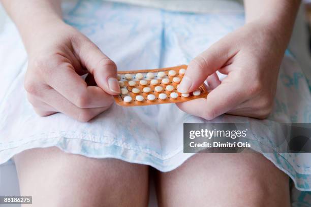 young woman holding "the pill" on her lap - birth control stock-fotos und bilder