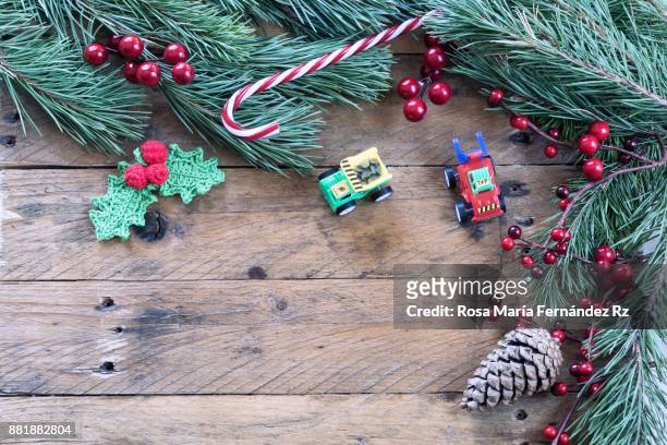 christmas decoration: toys, crochet mistletoe leaves, candy cane, pine cone, fir tree branches, and mistletoe seed on rustic wooden background. top view and copy space. - pungitopo foto e immagini stock