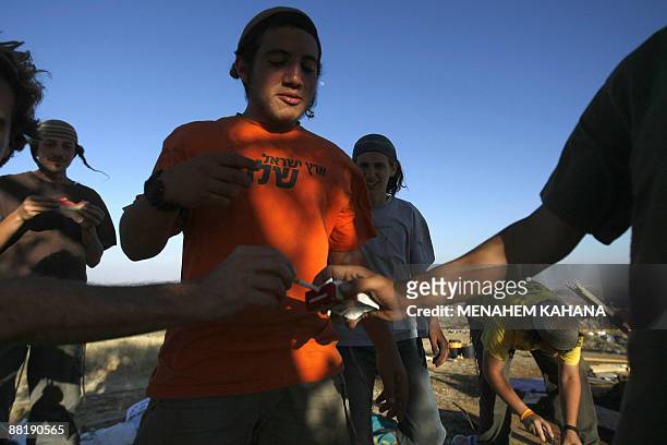 Jewish settler offers cigarettes to fellow settlers as they rebuild the destroyed Migron outpost in the occupied West Bank on June 3, 2009. Israeli...