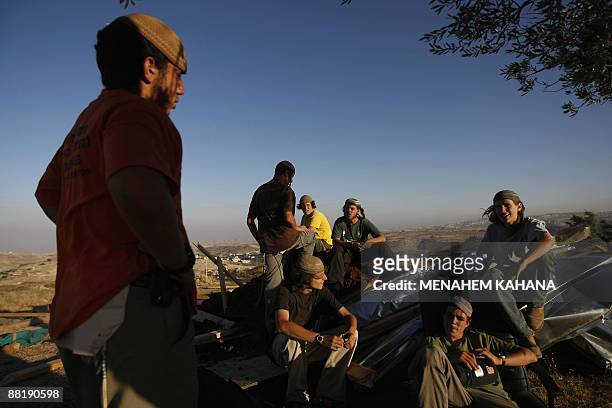 Jewish settlers sit over the rubble of the destroyed Migron outpost in the occupied West Bank on June 3, 2009. Israeli security forces destroyed nine...