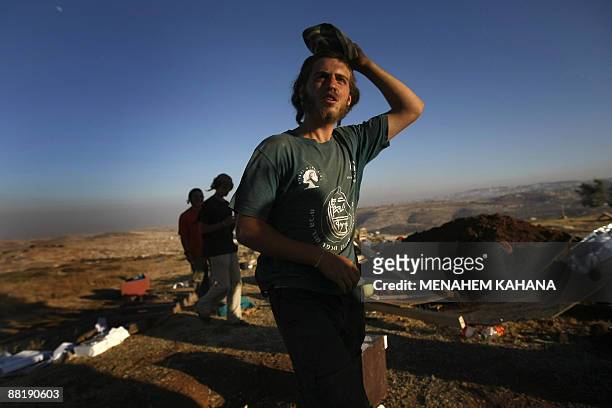 Jewish settlers walk at the destroyed Migron outpost in the occupied West Bank on June 3, 2009. Israeli security forces destroyed nine tin huts that...