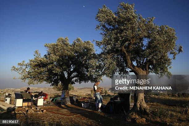 Jewish settlers sit under olive trees near the destroyed Migron outpost in the occupied West Bank on June 3, 2009. Israeli security forces destroyed...