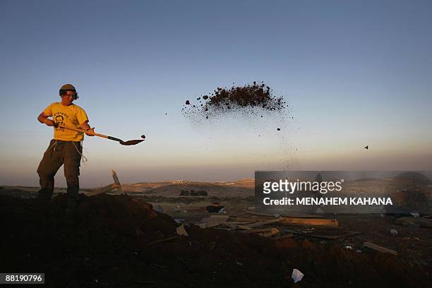 Jewish settler shovels dirt as he rebuilds the destroyed Migron outpost in the occupied West Bank on June 3, 2009. Israeli security forces destroyed...