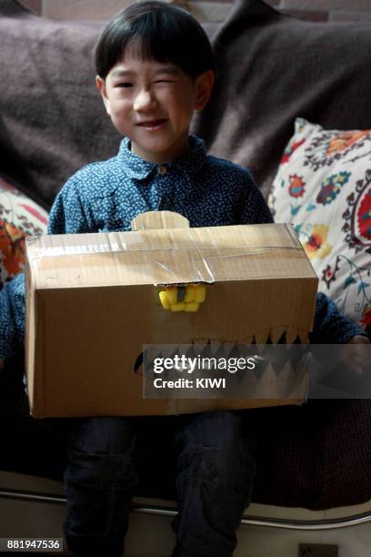 boy holding a dinosaur mask grimacing - reptile bedding stock pictures, royalty-free photos & images