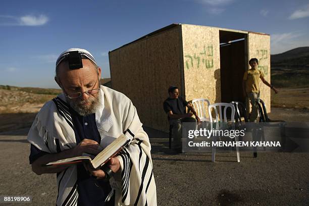 Jewish settler wearing a prayer shawl recites prayers next to a wooden cabin built outside the West Bank settlement Shilo, on June 4 the day after...