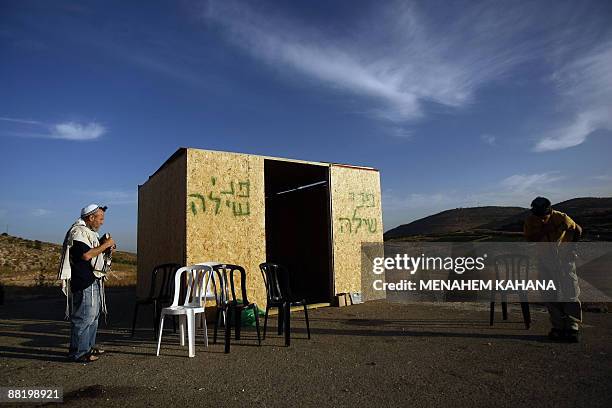 Jewish settler wearing a prayer shawl recites prayers next to a wooden cabin built outside the West Bank settlement Shilo, on June 4 the day after...