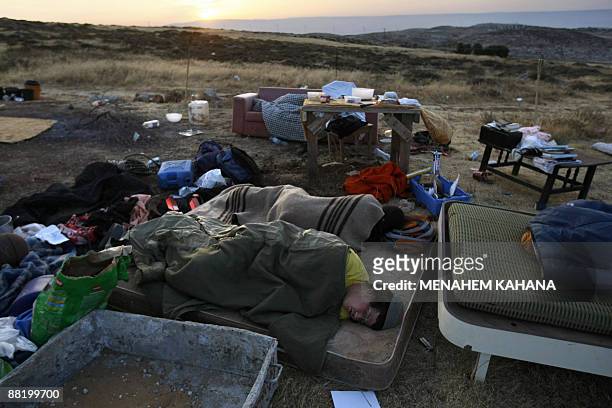 Jewish settlers sleep and smoke at their destroyed outpost near the Migron settlement in the West Bank on June 4 the day after Israeli security...