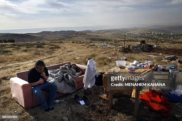 Jewish settlers sleep and smoke at their destroyed outpost near the Migron settlement in the West Bank on June 4 the day after Israeli security...