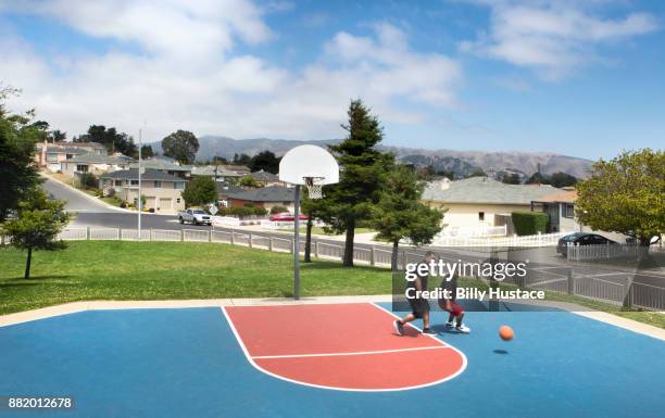 men playing a basketball game in a public park. - suburb park stock pictures, royalty-free photos & images